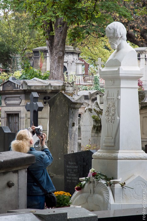 Женщина фотографирует скульптуру на кладбище